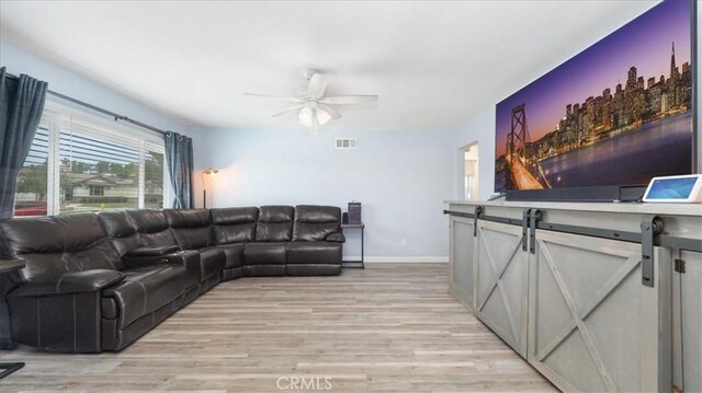 living room featuring visible vents, a ceiling fan, baseboards, and light wood-type flooring