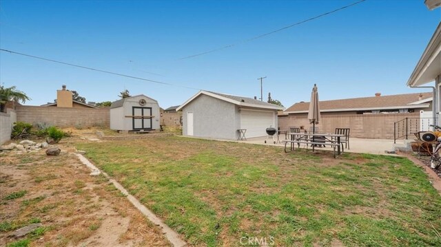 view of yard with an outdoor structure, a fenced backyard, and a shed