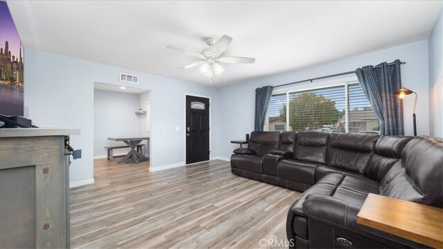 living room featuring visible vents, baseboards, ceiling fan, and light wood-type flooring