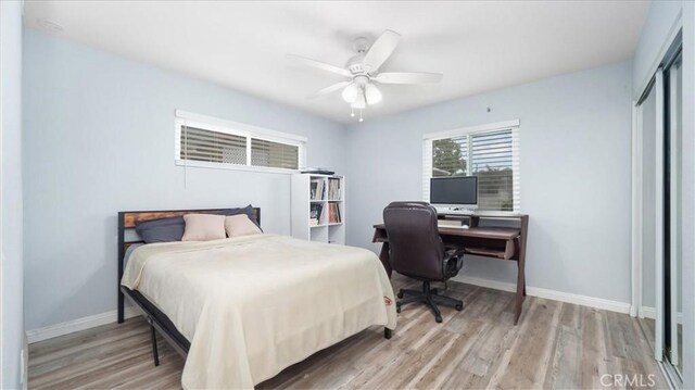 bedroom featuring light wood-type flooring, a ceiling fan, and baseboards