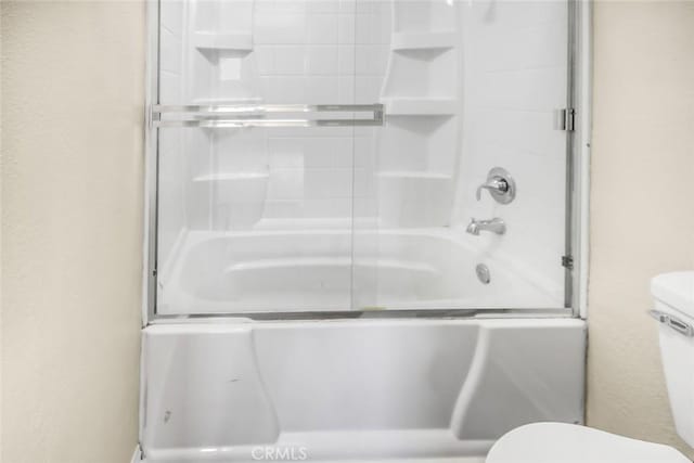 bathroom featuring a textured wall, a shower with shower door, and toilet