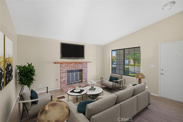 living room featuring baseboards, vaulted ceiling, wood finished floors, and a brick fireplace