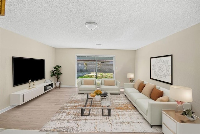 living area with baseboards, light wood finished floors, and a textured ceiling