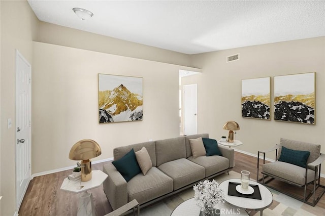 living area featuring baseboards, wood finished floors, and visible vents