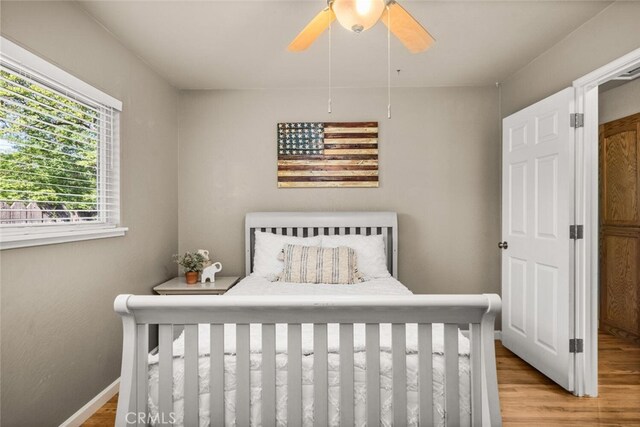 bedroom with a ceiling fan, baseboards, and light wood-style floors