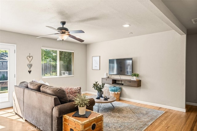 living area featuring baseboards, ceiling fan, wood finished floors, and visible vents