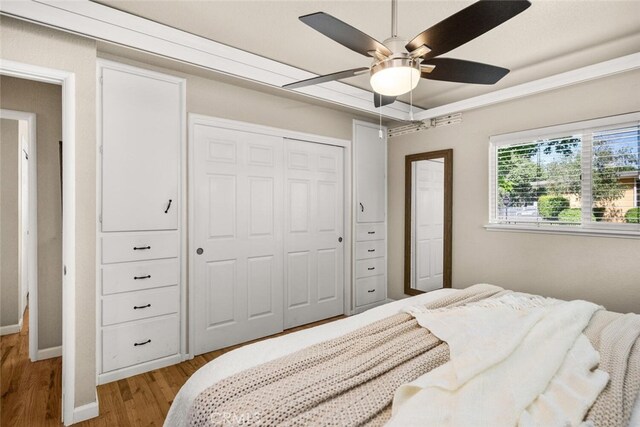 bedroom with ceiling fan, baseboards, wood finished floors, visible vents, and a closet