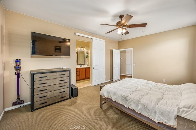 bedroom with baseboards, light carpet, ceiling fan, and ensuite bath