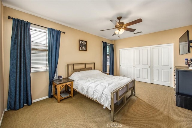bedroom with baseboards, visible vents, light carpet, and a closet