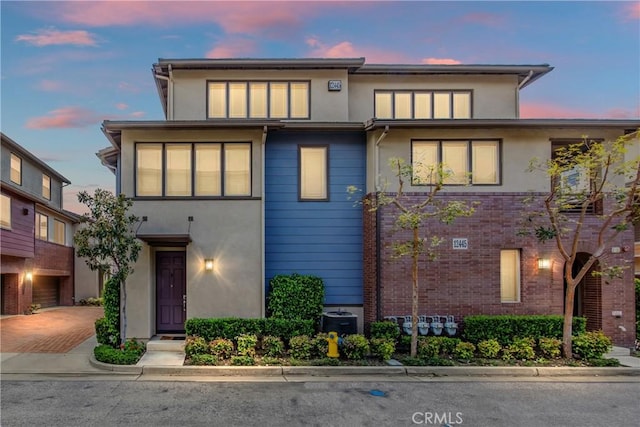 view of front of home with decorative driveway, cooling unit, and stucco siding