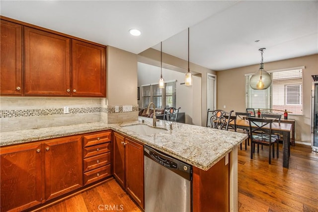 kitchen featuring stainless steel dishwasher, a peninsula, dark wood-style floors, and a sink