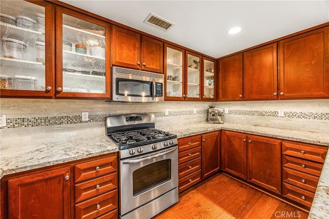 kitchen featuring appliances with stainless steel finishes, wood finished floors, visible vents, and tasteful backsplash