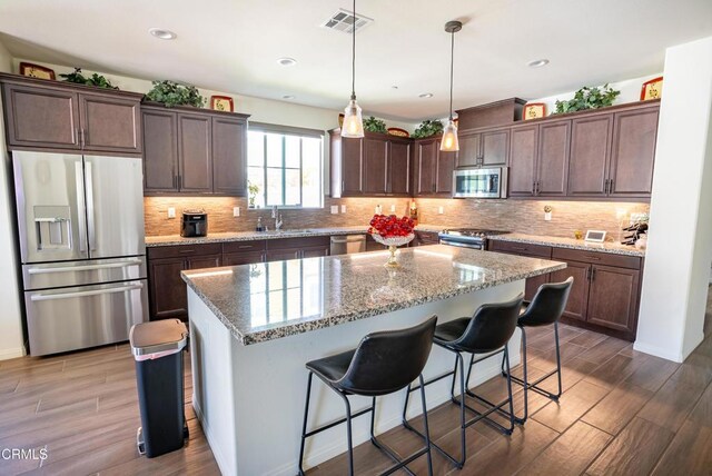 kitchen with visible vents, a center island, dark wood finished floors, backsplash, and stainless steel appliances