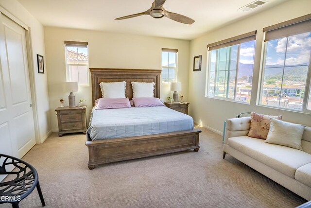 bedroom featuring visible vents, a ceiling fan, baseboards, and light carpet