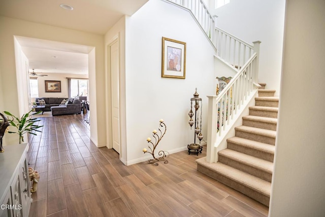 hall featuring stairs, baseboards, and wood finished floors