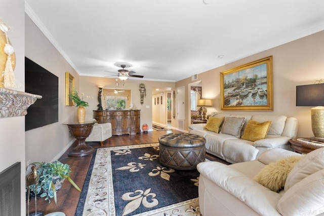 living room with a ceiling fan, visible vents, wood finished floors, baseboards, and ornamental molding