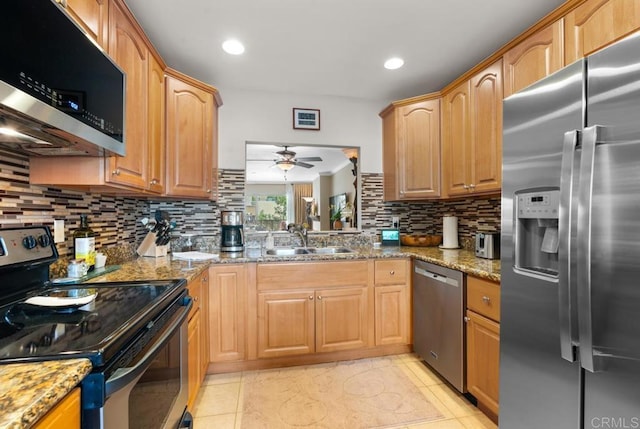 kitchen featuring stone countertops, appliances with stainless steel finishes, a sink, and tasteful backsplash