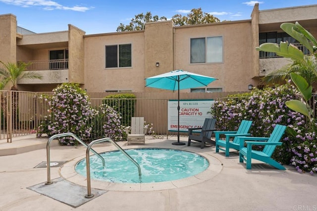 view of pool with a hot tub and fence
