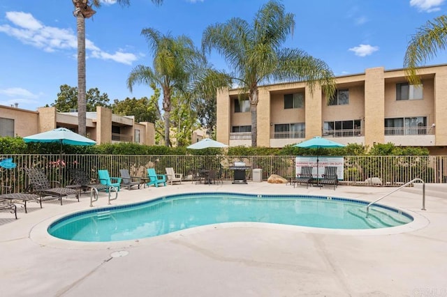pool with fence, a patio, and area for grilling