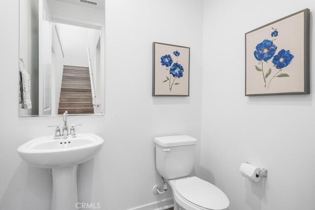 bathroom with toilet, baseboards, and visible vents