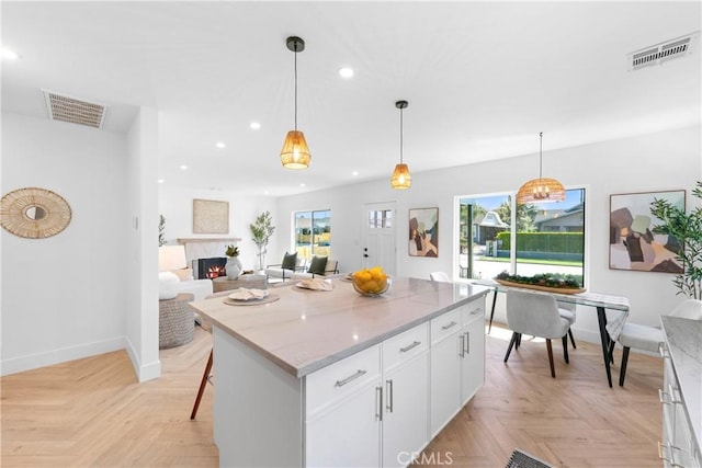 kitchen with recessed lighting, a warm lit fireplace, visible vents, and a wealth of natural light