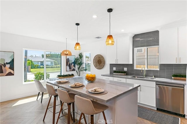 kitchen featuring a center island, tasteful backsplash, stainless steel dishwasher, a sink, and recessed lighting