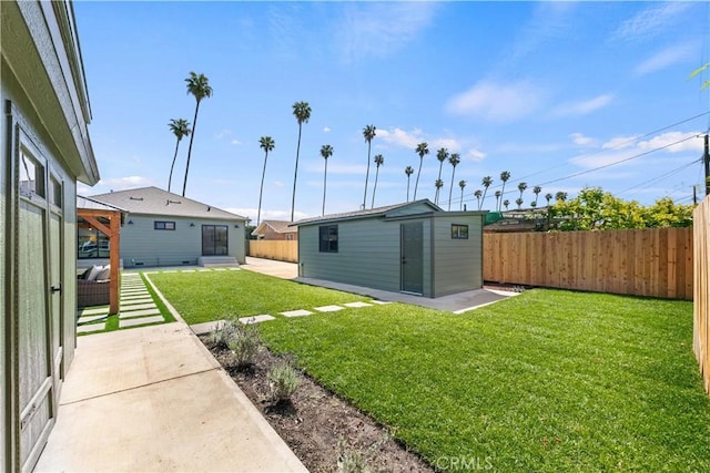 view of yard with an outbuilding, a fenced backyard, and a patio area