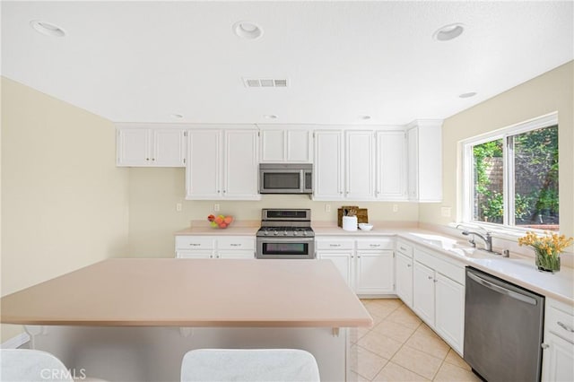 30526 Beryl Pl, Castaic, CA 91384 - kitchen featuring appliances with stainless steel finishes, a sink, white cabinetry, light tile patterned floors, and visible vents