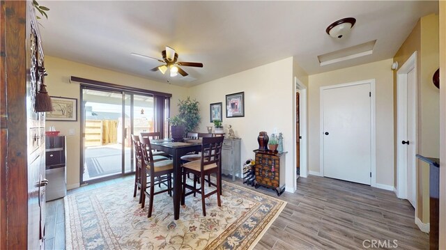 dining area with baseboards, ceiling fan, attic access, and light wood-style flooring