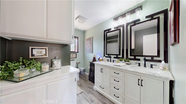 full bathroom with a sink, toilet, double vanity, and wood finished floors