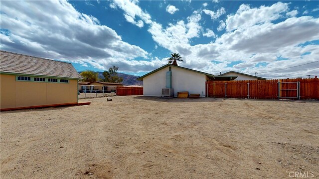 rear view of property with central air condition unit, fence, and stucco siding