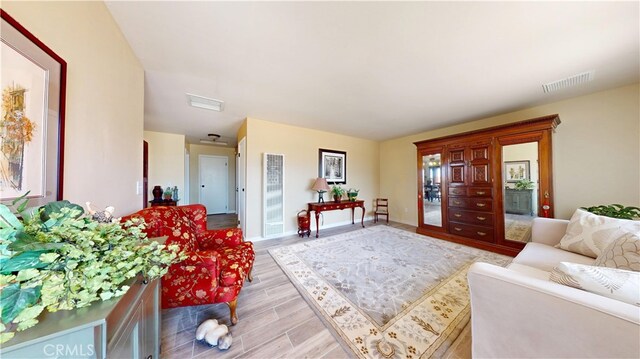 living area with a heating unit, baseboards, light wood finished floors, and visible vents