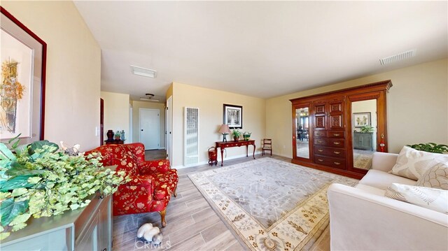 living room with visible vents, a heating unit, light wood-style flooring, and baseboards