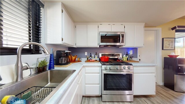 kitchen featuring a sink, light countertops, light wood-style floors, and stainless steel appliances