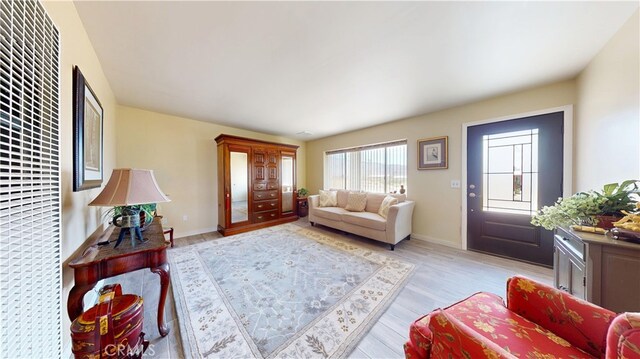 living room featuring light wood-type flooring, a heating unit, and baseboards