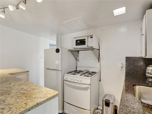 16855 12th St, Sunset Beach, CA 90742 - kitchen featuring white appliances, white cabinetry, a sink, and light stone counters