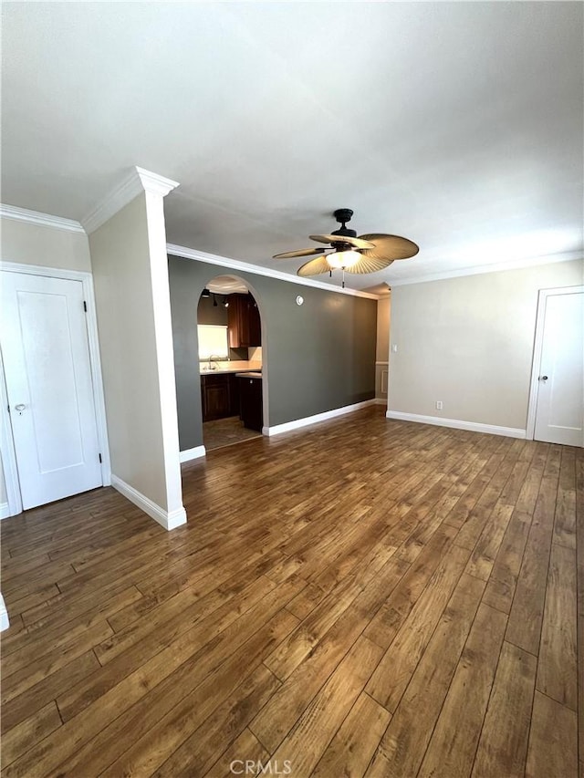 unfurnished living room featuring baseboards, ornamental molding, a ceiling fan, and dark wood-style flooring
