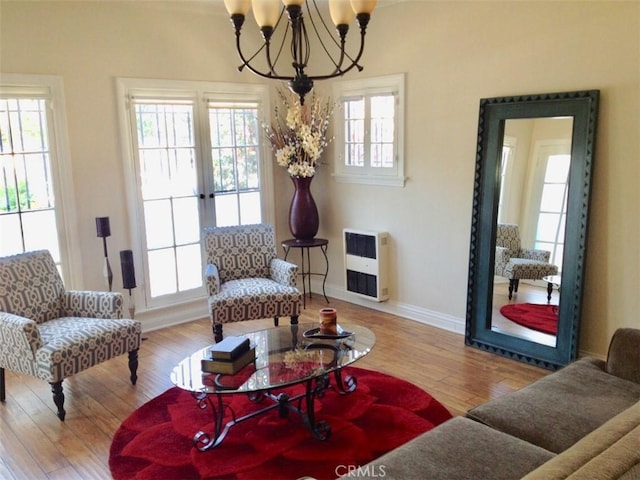 interior space with an inviting chandelier, heating unit, wood-type flooring, and baseboards