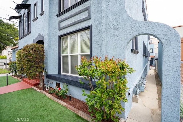view of side of property featuring a lawn and stucco siding