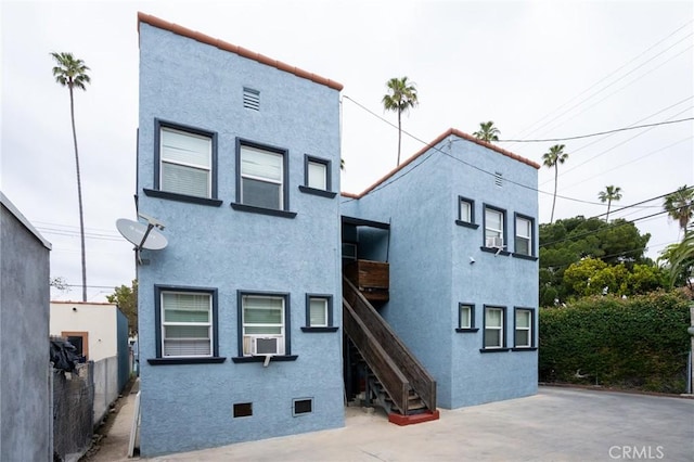 back of property with fence, stairs, and stucco siding