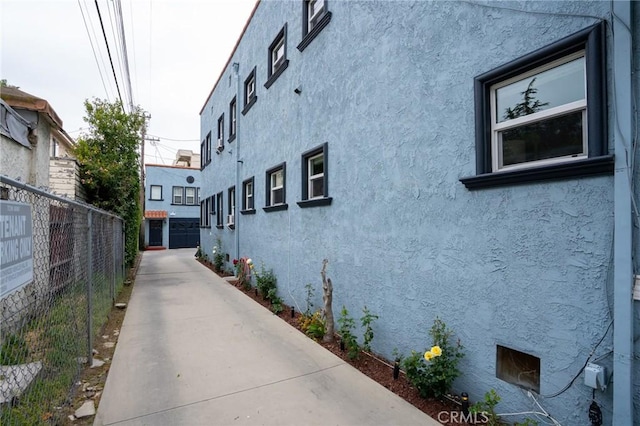 view of side of property with fence and stucco siding