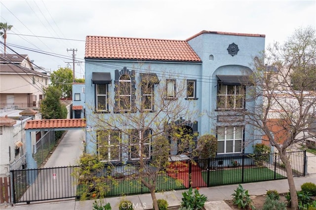 view of front of house featuring a gate, a fenced front yard, stucco siding, and a tiled roof