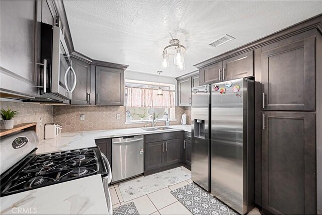 875 S Rexford St, Rialto, CA 92376 - kitchen with appliances with stainless steel finishes, a sink, tasteful backsplash, light stone countertops, and dark brown cabinets