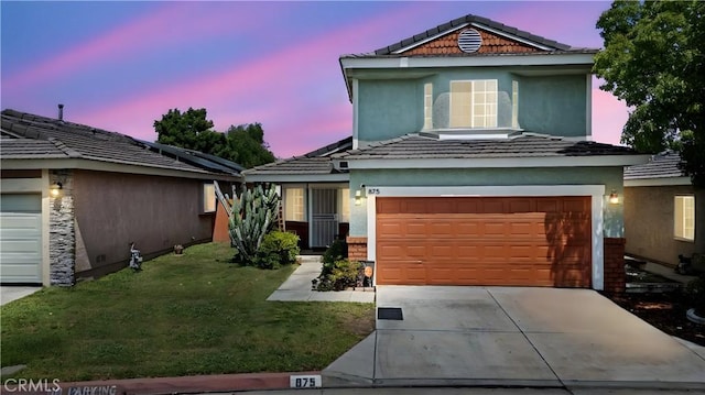 875 S Rexford St, Rialto, CA 92376 - traditional-style house with a yard, concrete driveway, stucco siding, a garage, and a tiled roof