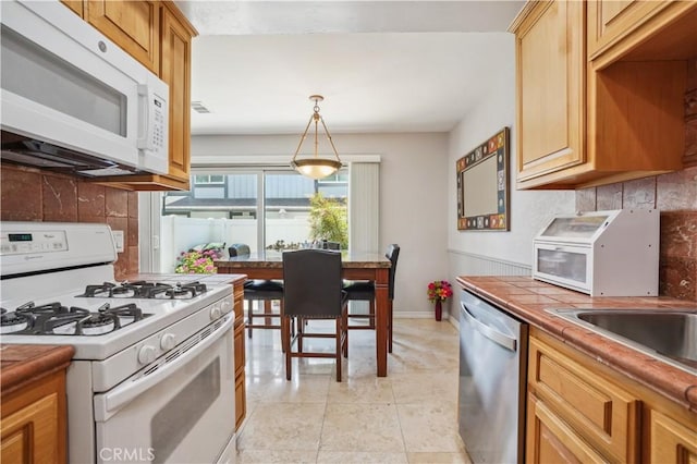kitchen with backsplash, hanging light fixtures, baseboards, tile counters, and white appliances