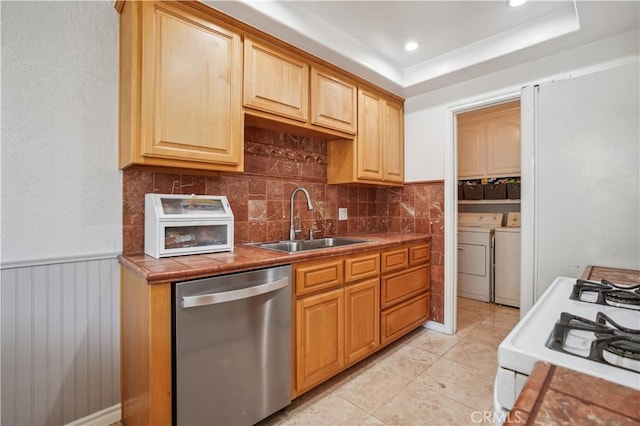 kitchen featuring independent washer and dryer, a sink, dishwasher, white gas stove, and backsplash