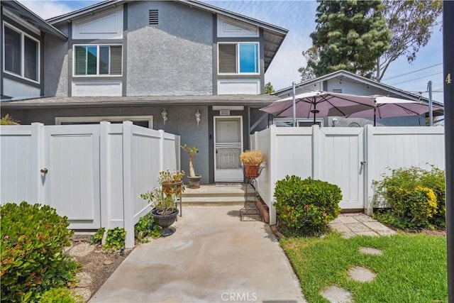 view of front of home with fence, a gate, and stucco siding