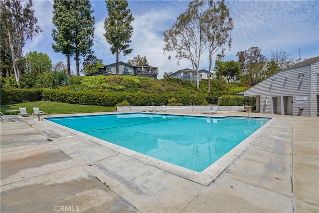 community pool featuring a lawn and a patio area