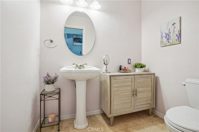 half bath with baseboards, a sink, tile patterned floors, and toilet