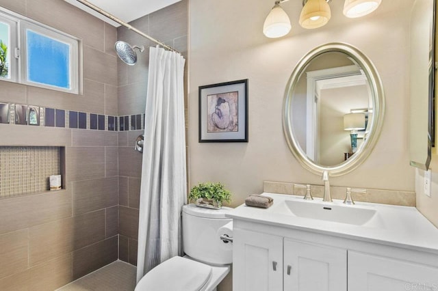 bathroom featuring toilet, tiled shower, and vanity